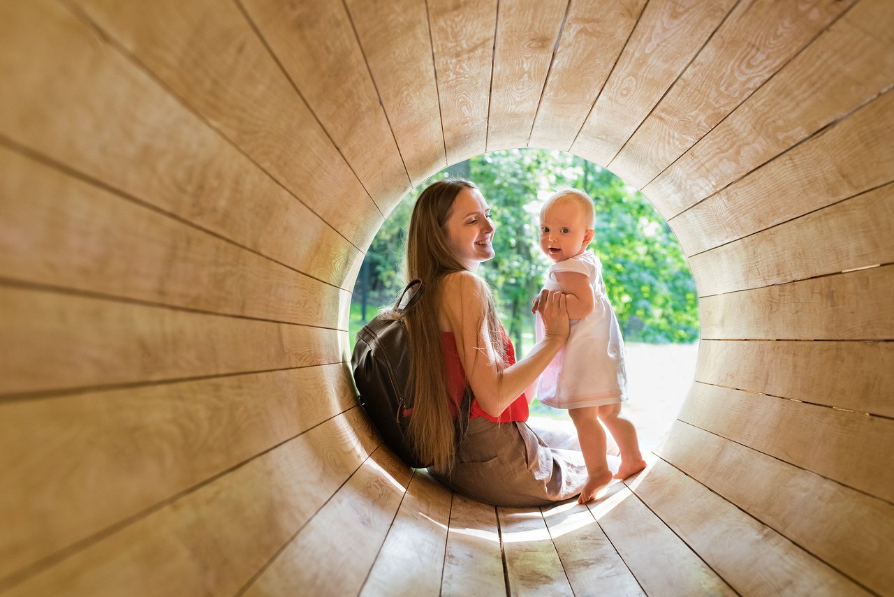 Mother and Baby Playing on the Playground in the Wooden Tunnel